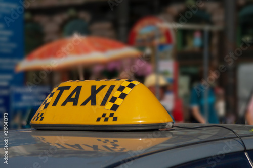 taxi cap on a car roof against the city
