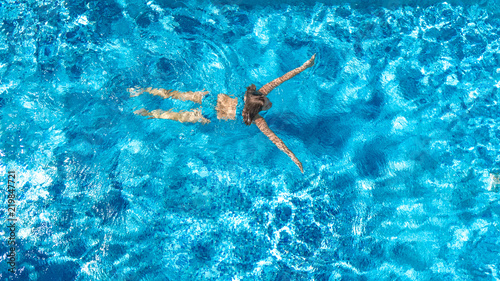 Aerial top view of active woman in swimming pool from above  girl swims in blue water  tropical vacation  holiday on resort concept  