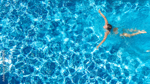 Aerial top view of active woman in swimming pool from above, girl swims in blue water, tropical vacation, holiday on resort concept 