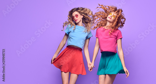 Full-length portrait Two Girl with Wavy Hairstyle Having Fun Dance. Young Beautiful Pretty Model Woman in Fashion Stylish Summer Outfit. Crazy Sisters Friends laughing on Purple