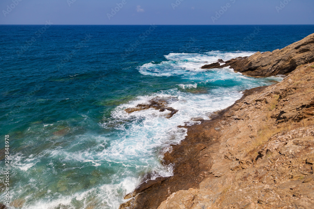 Blue sea waves on a rocky beach, Crete, Greece. Mediterranean coast. Travel and vacation on the beach. Beautiful seascape..
