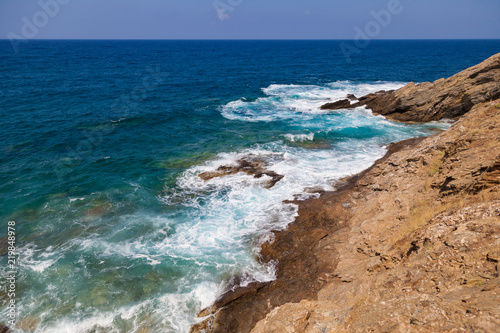 Blue sea waves on a rocky beach, Crete, Greece. Mediterranean coast. Travel and vacation on the beach. Beautiful seascape..