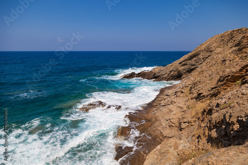 Blue sea waves on a rocky beach, Crete, Greece. Mediterranean coast. Travel and vacation on the beach. Beautiful seascape.