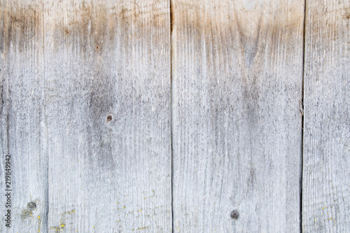 background: grey, sun-bleached boards in a wooden fence with cracks, traces of age and damp, the upper part of the boards is the best preserved