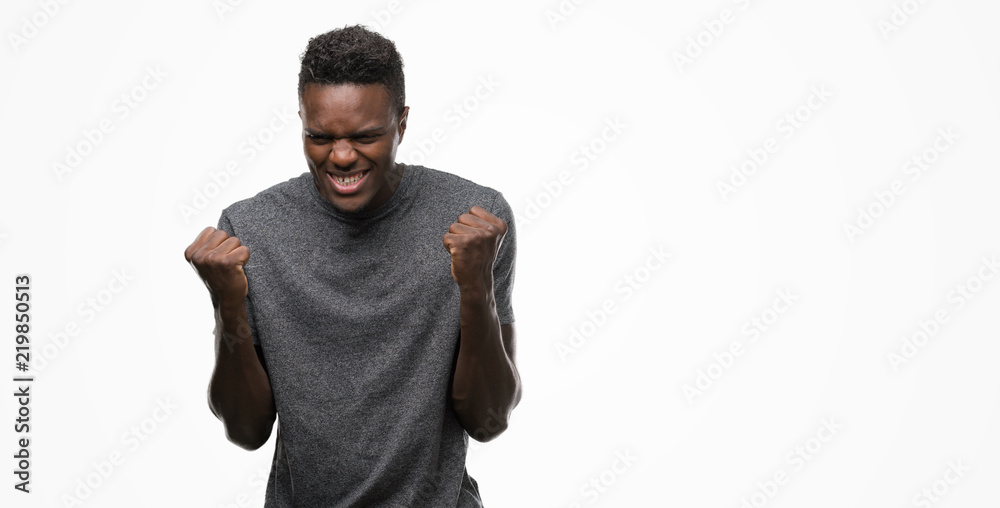 Young african american man wearing grey t-shirt celebrating surprised and amazed for success with arms raised and open eyes. Winner concept.