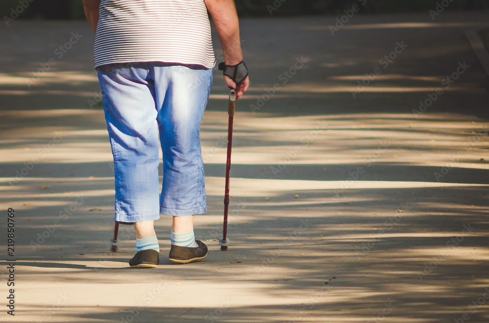 An elderly woman is engaged in Scandinavian walk in the park, Russia. An elderly woman is engaged in Scandinavian walk in the park, Russia.