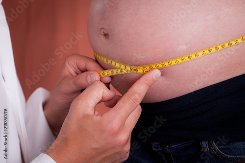 Measuring Waistline of an Overweight Patient with Tape Measure photo