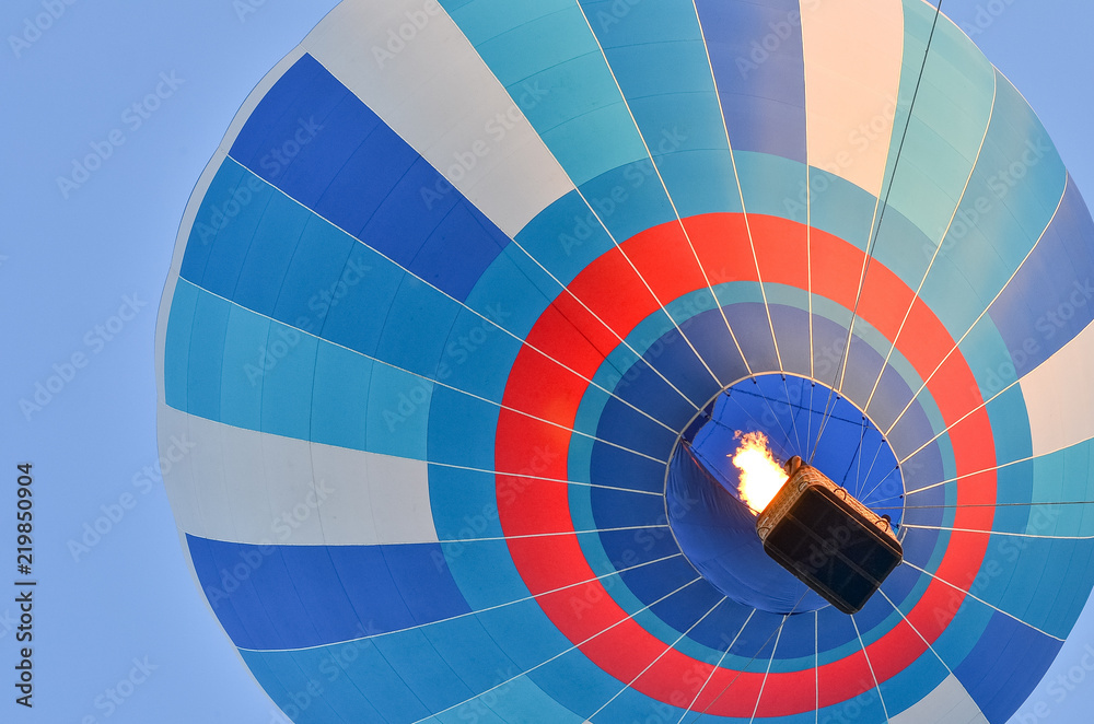 Fototapeta premium Close up of a colorful hot air balloon in blue sky. Bottom view.