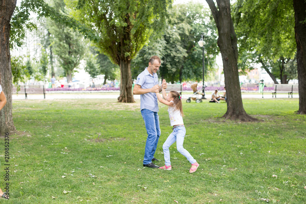 daughter and mother spinning on the lawn.in a white t-shirt and jeans. a walk in the Park. child. mother-daughter. summer. daughter and mother spinning on the lawn.in a white t-shirt and jeans. a walk in the Park. child. mother-daughter. summer.