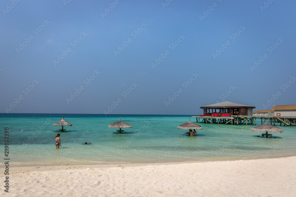 Maldives, Feb 8th 2018 - Tourists enjoying a calm beach, blue water, tropical climate, no waves in a blue sky day in Maldives.