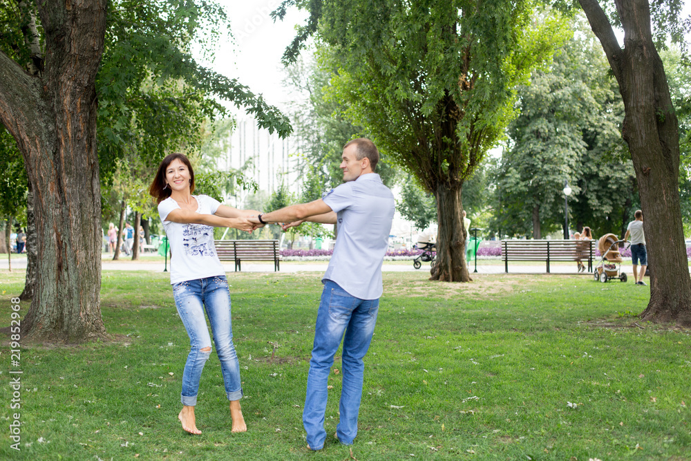 man and woman sitting on the lawn. in a white t-shirt and jeans. a walk in the Park. lover. young couple. summer. family. embrace man and woman sitting on the lawn. in a white t-shirt and jeans. a walk in the Park. lover. young couple. summer. family. embrace