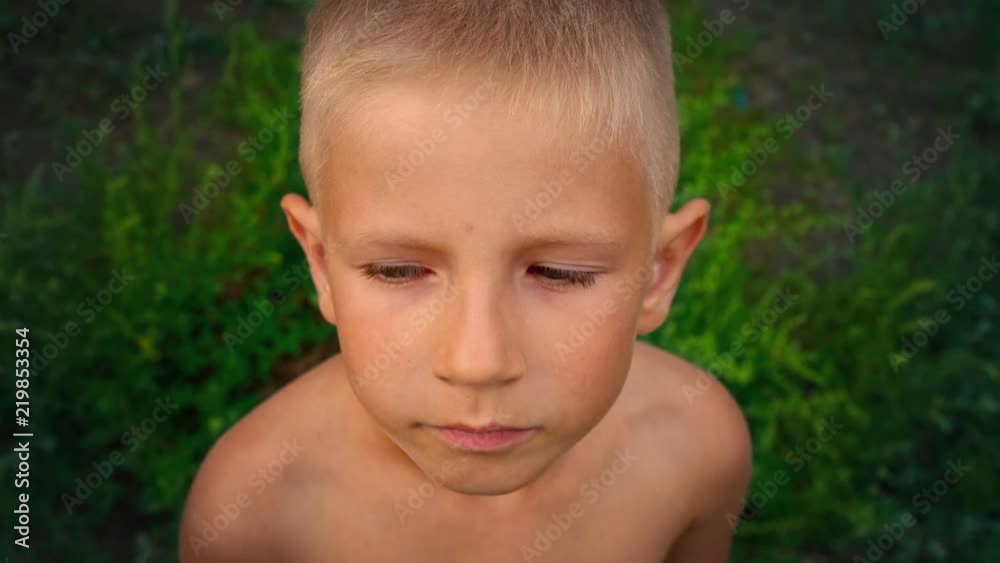 Close-up portrait of a blue-eyed little boy looking directly at the camera and tries to smile, a piercing look of a 6-year-old child, view from above Close-up portrait of a blue-eyed little boy looking directly at the camera and tries to smile, a piercing look of a 6-year-old child, view from above