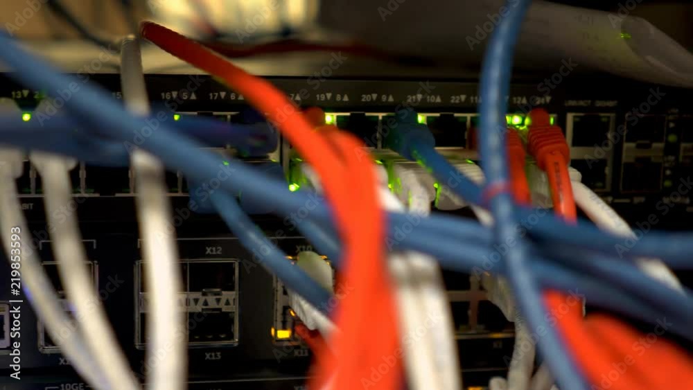 Scene tracks past the multicolored cables and blinking green lights of