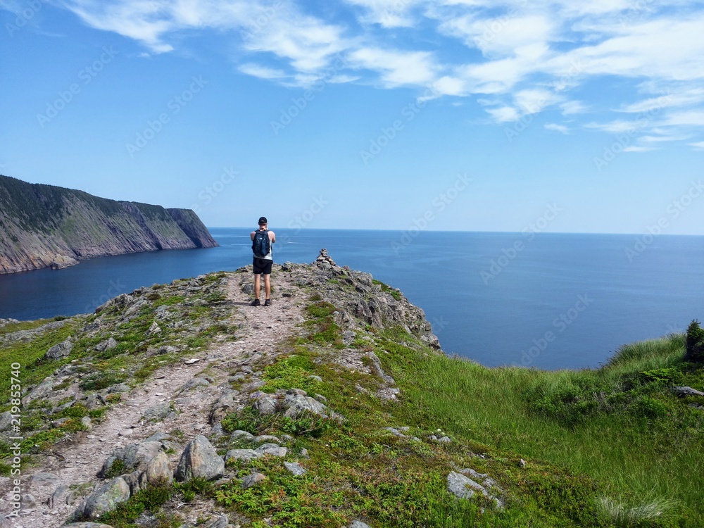 Man taking a photo on his camera of the open and calm atlantic ocean along the sugarloaf trail in Newfoundland and Labrador, Canada