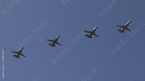 Several military fighters are flying in a formation against the blue sky