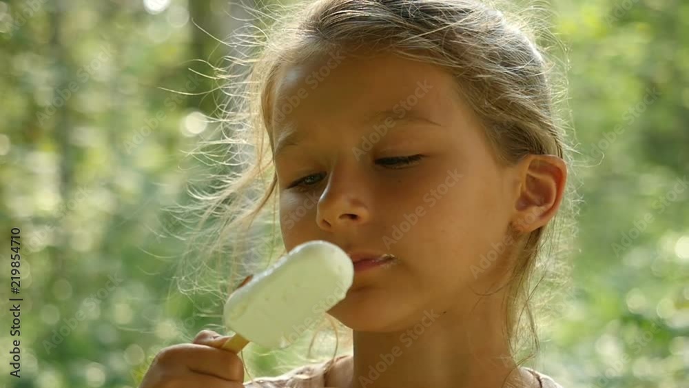 Little girl licking ice-cream. Charming child eats ice cream outdoors Little girl licking ice-cream. Charming child eats ice cream outdoors