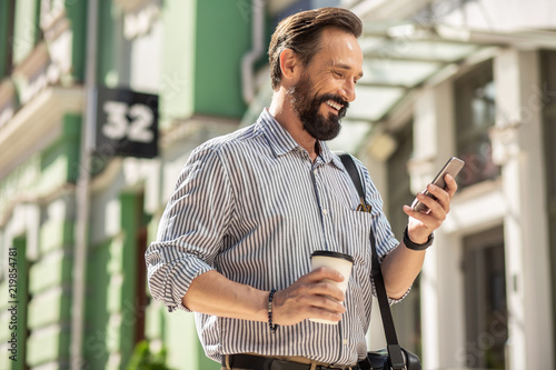 Positive adult man drinking coffee on his way to work