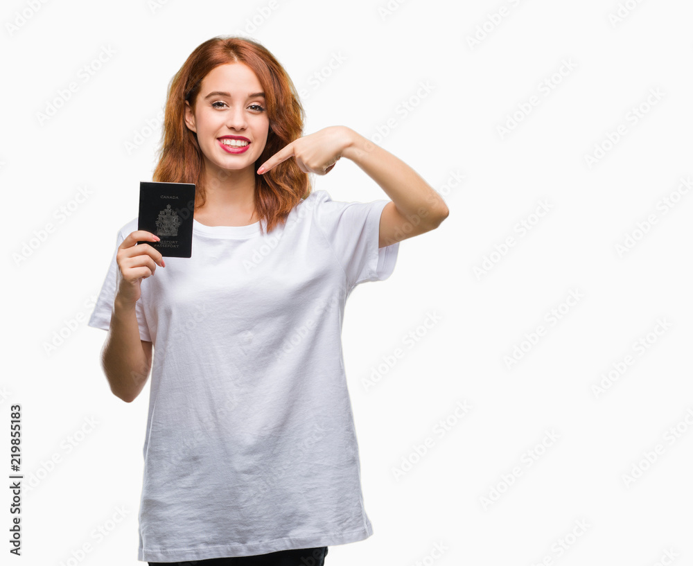 Young beautiful woman holding passport of canada over isolated background very happy pointing with hand and finger Young beautiful woman holding passport of canada over isolated background very happy pointing with hand and finger