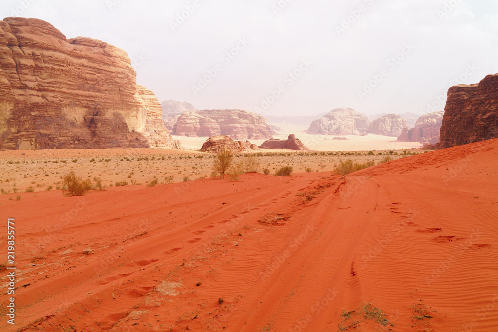 Wadi Rum desert, Jordan, Middle East, known as The Valley of the Moon. Orange sand, blue sky, haze and clouds. Designation as a UNESCO World Heritage Site. Red planet Mars landscape. Wadi Rum desert, Jordan, Middle East, known as The Valley of the Moon. Orange sand, blue sky, haze and clouds. Designation as a UNESCO World Heritage Site. Red planet Mars landscape.