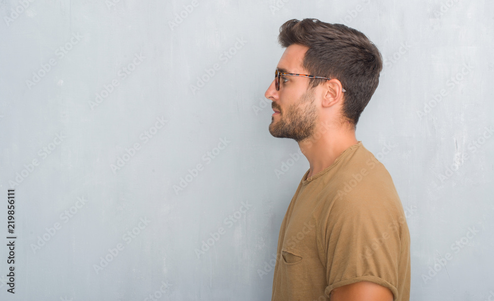 Handsome young man over grey grunge wall wearing glasses looking to side,  relax profile pose with natural face with confident smile. Stock Photo |  Adobe Stock