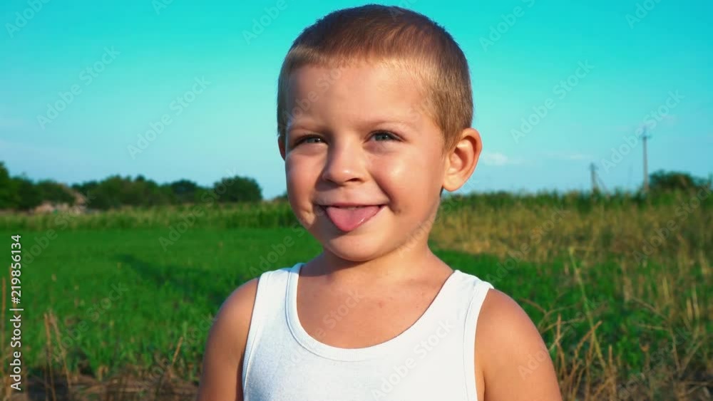 Vidéo Stock 4yearold boy in a white tshirt smiles and shows tongue