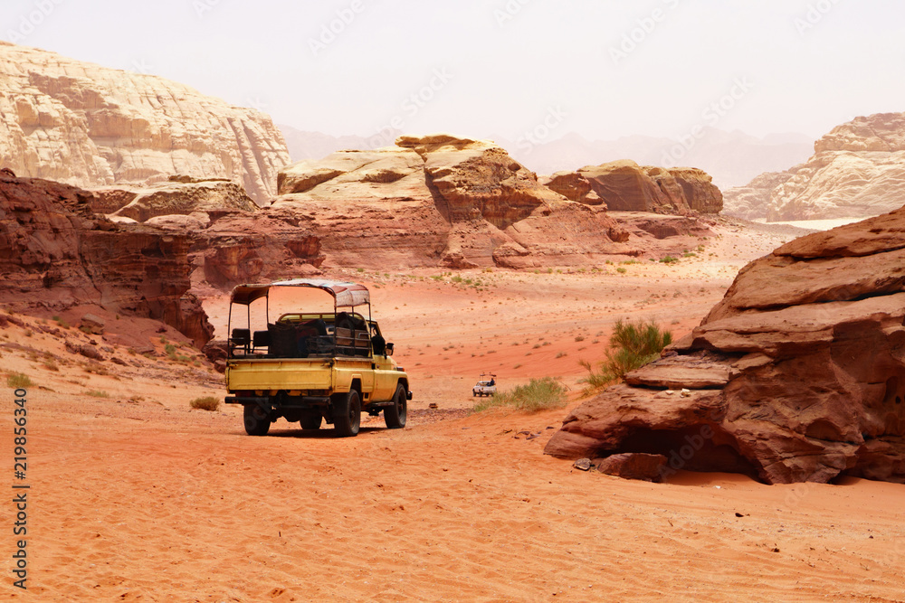 Offroad travel adventures safari jeep car in Wadi Rum desert, Jordan, Middle East, known as The Valley of the Moon. Red sands, sky with haze. Designation as a UNESCO World Heritage Site.