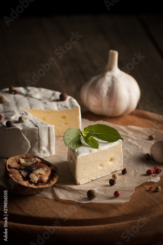 Fotografia Camembert and brie cheese on wooden background with tomatoes, letuce and garlic