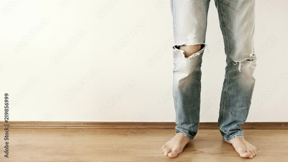 Dancing legs in torn jeans against the white wall Dancing legs in torn jeans against the white wall