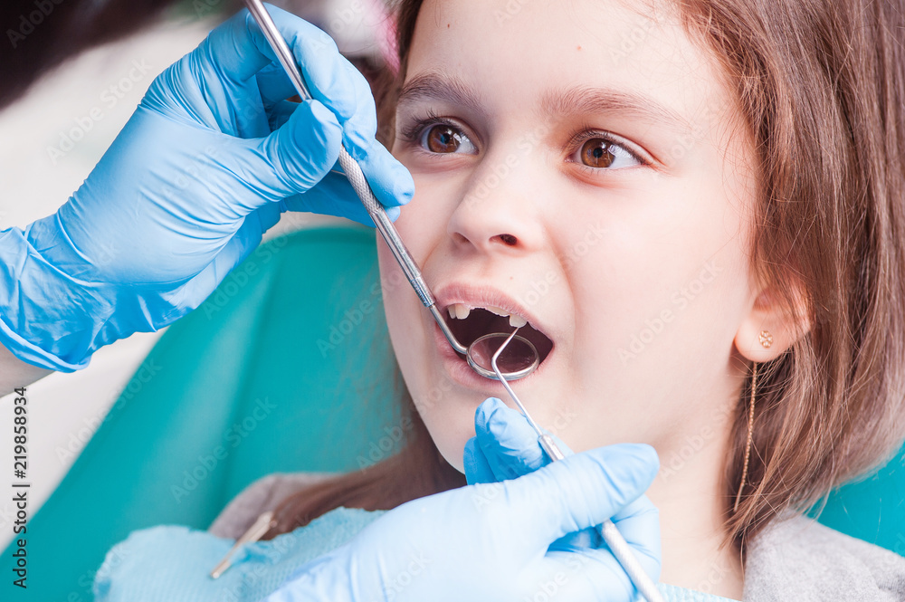 The dentist examines the teeth of a little girl. Close-up The dentist examines the teeth of a little girl. Close-up