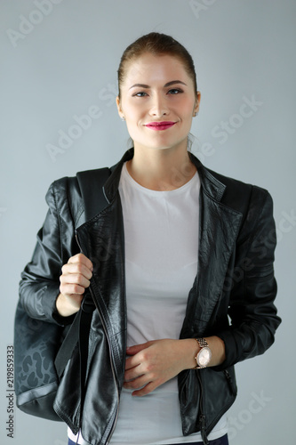 portrait of beautiful young brunette woman in stylish black jacket on gray. photo