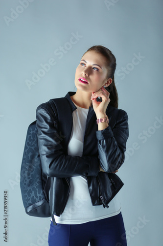 portrait of beautiful young brunette woman in stylish black jacket on gray. photo