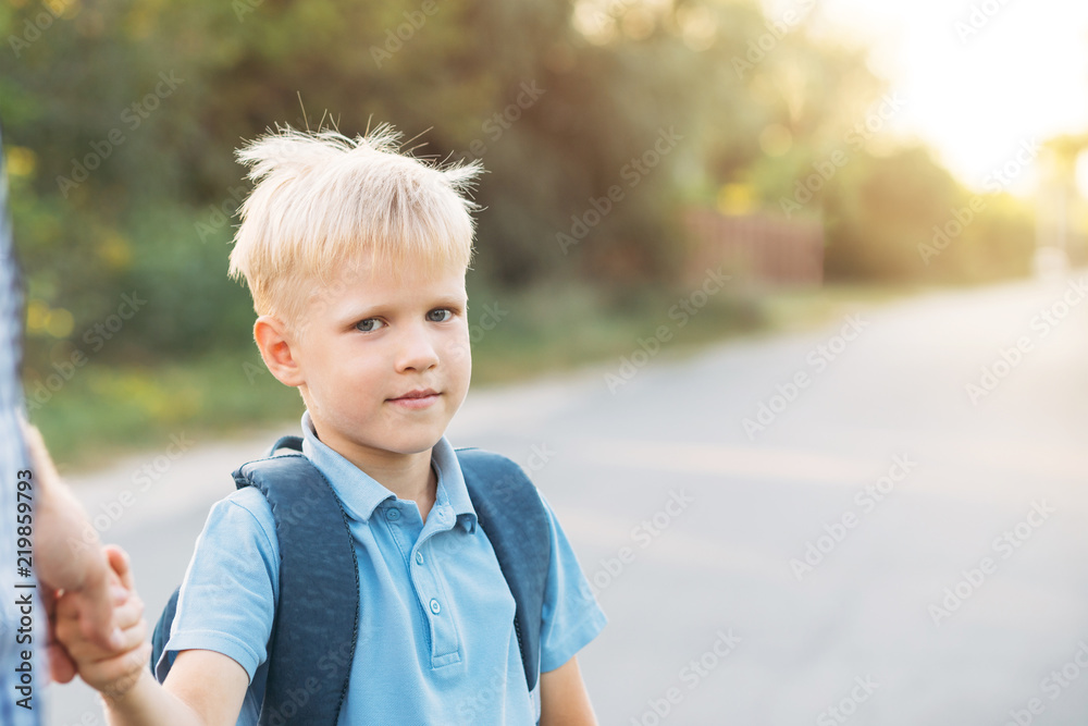 Father holding little son's hand. Little schoolboy with backpack looking at the camera and going to school. Back to school concept. Father holding little son's hand. Little schoolboy with backpack looking at the camera and going to school. Back to school concept.