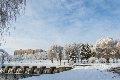 winter park, different trees covered with snow, artificial waterfall on the background of houses © Анастасия Гайкова