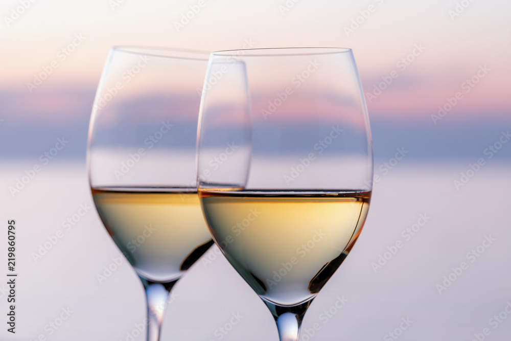 Two glasses of white wine against the evening sky, close-up