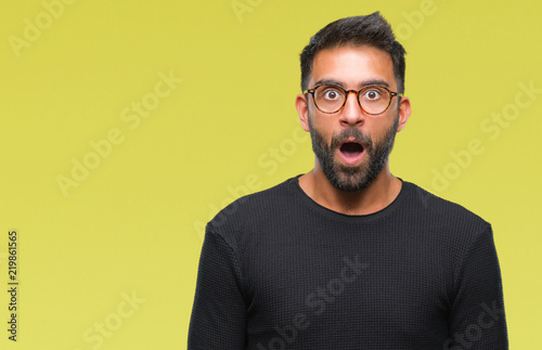 Adult hispanic man wearing glasses over isolated background afraid and shocked with surprise expression, fear and excited face.