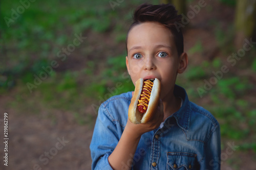a young boy takes a bite of a hot dog