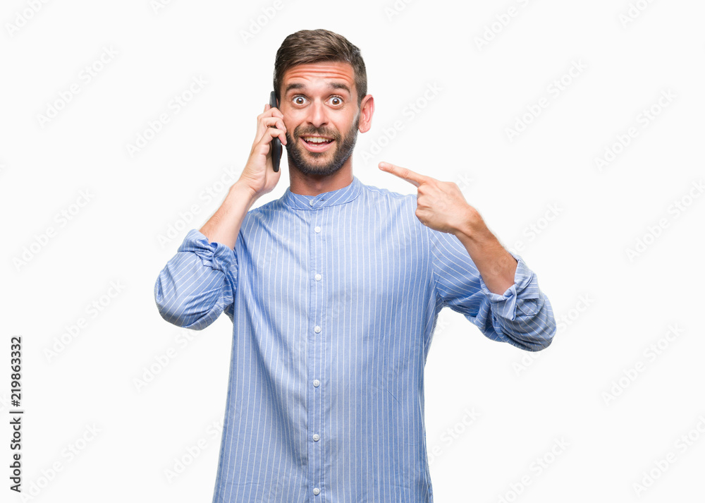 Young handsome man speaking on the phone over isolated background very happy pointing with hand and finger Young handsome man speaking on the phone over isolated background very happy pointing with hand and finger