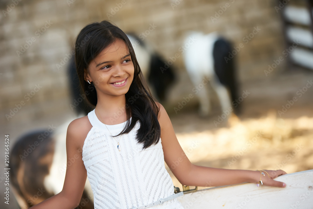 Beautiful young girl and horses. Cute smiling girl with long dark hear 