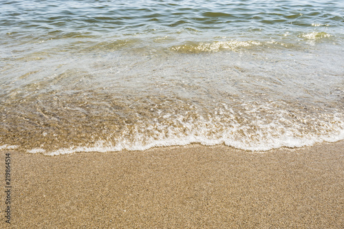 sea shoreline with waves, sandy beach on a clear sunny day, close-up nature abstract background