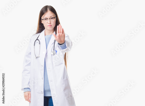 Young Chinese doctor woman over isolated background doing stop sing with palm of the hand. Warning expression with negative and serious gesture on the face.