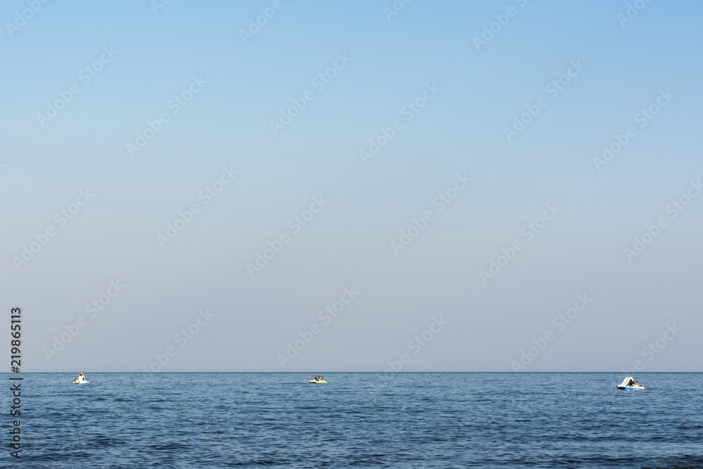 blue sea with waves, far away on a horizon line floating three catamarans with people blue sea with waves, far away on a horizon line floating three catamarans with people