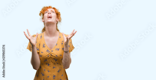 Young redhead woman crazy and mad shouting and yelling with aggressive expression and arms raised. Frustration concept.