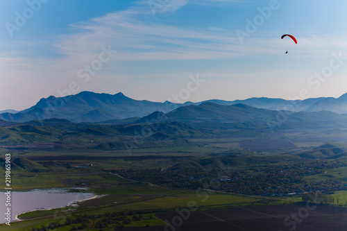 Experienced hang-glider hovering above hilly landscape