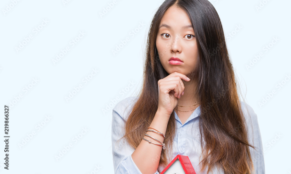 Young asian woman real state agent holding house isolated background serious face thinking about question, very confused idea Young asian woman real state agent holding house isolated background serious face thinking about question, very confused idea