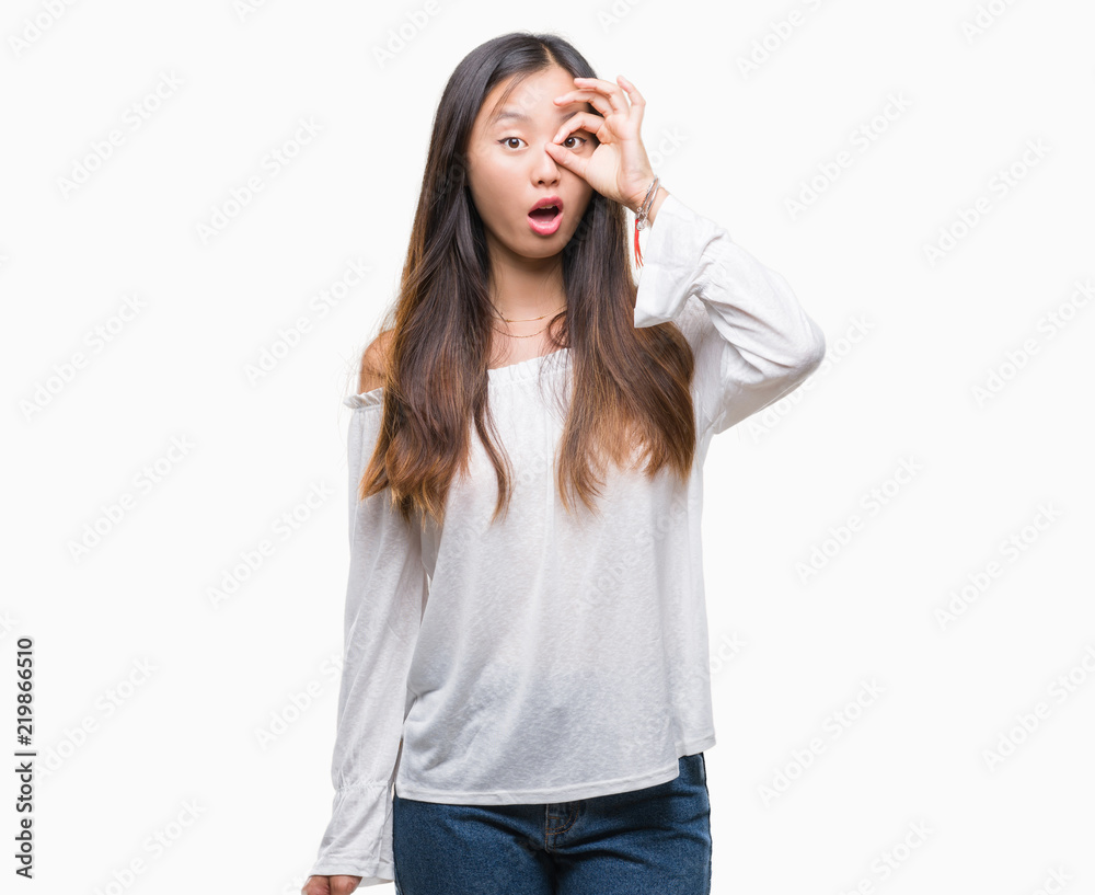 Young asian woman over isolated background doing ok gesture shocked with surprised face, eye looking through fingers. Unbelieving expression. Young asian woman over isolated background doing ok gesture shocked with surprised face, eye looking through fingers. Unbelieving expression.