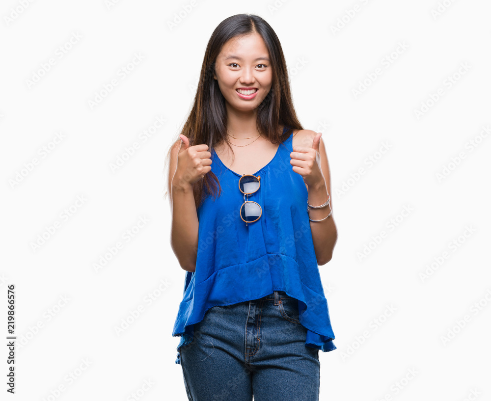 Young asian woman over isolated background success sign doing positive gesture with hand, thumbs up smiling and happy. Looking at the camera with cheerful expression, winner gesture. Young asian woman over isolated background success sign doing positive gesture with hand, thumbs up smiling and happy. Looking at the camera with cheerful expression, winner gesture.