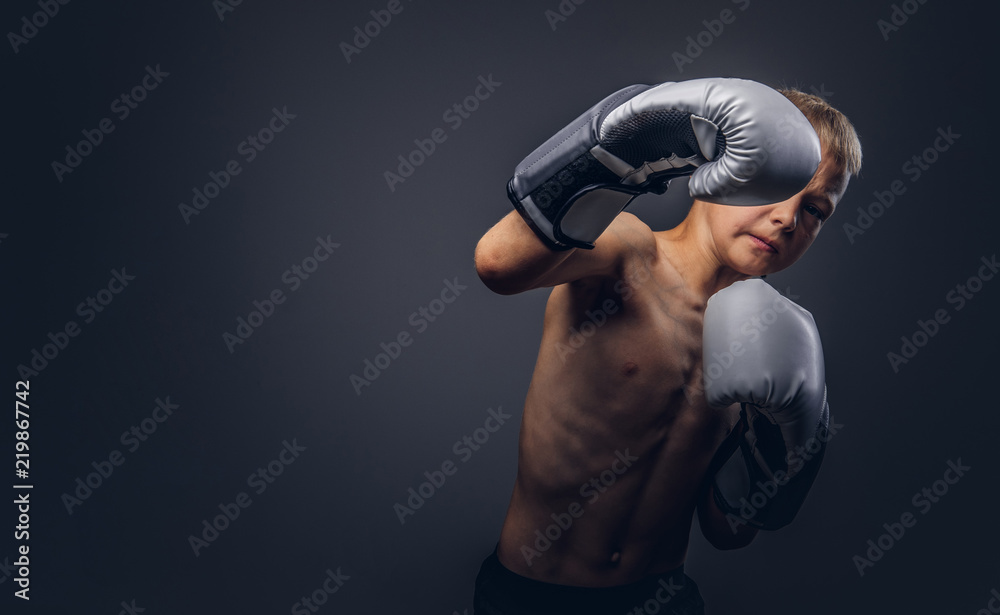 Shirtless young boxer with blonde hair wearing boxing gloves shows a boxing  hook. Stock Photo
