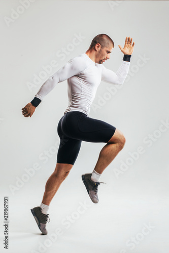 Fit and muscular man jumping/ Studio shoot of fit athlete jumping against white background