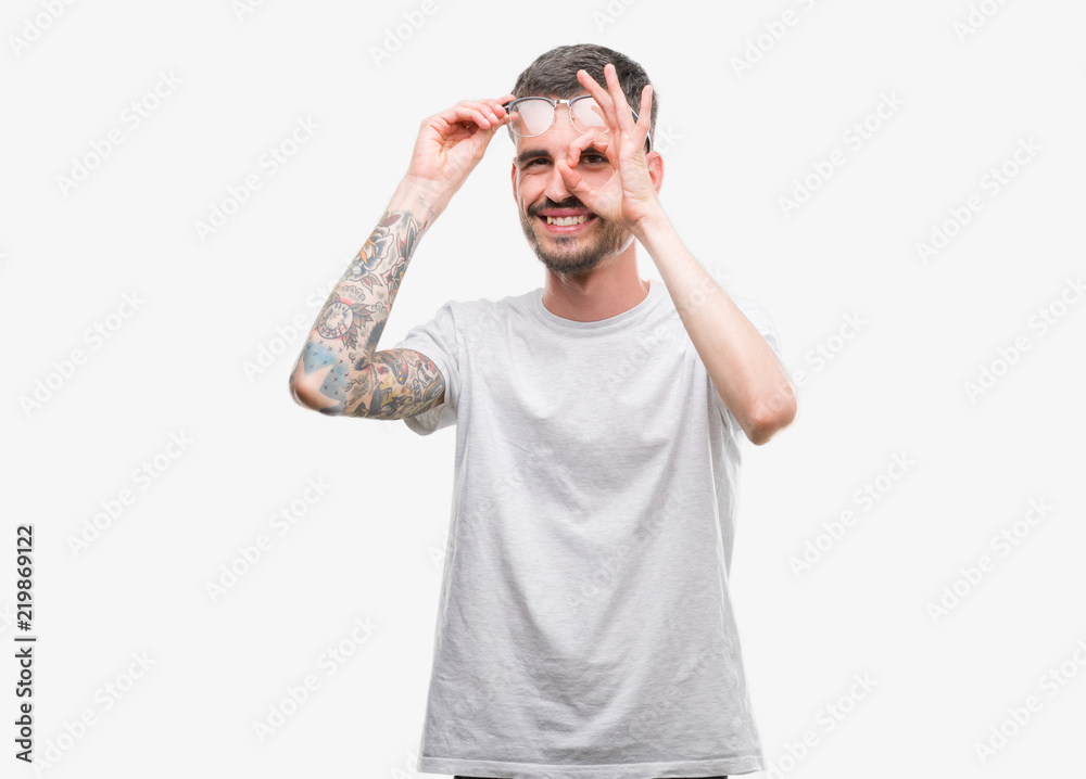 Fototapeta premium Young tattooed adult man doing ok gesture with hand smiling, eye looking through fingers with happy face.