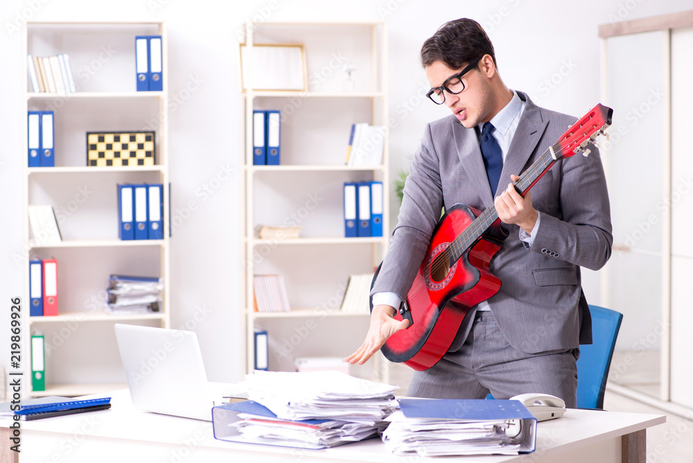 Young handsome businessman playing guitar in the office Young handsome businessman playing guitar in the office